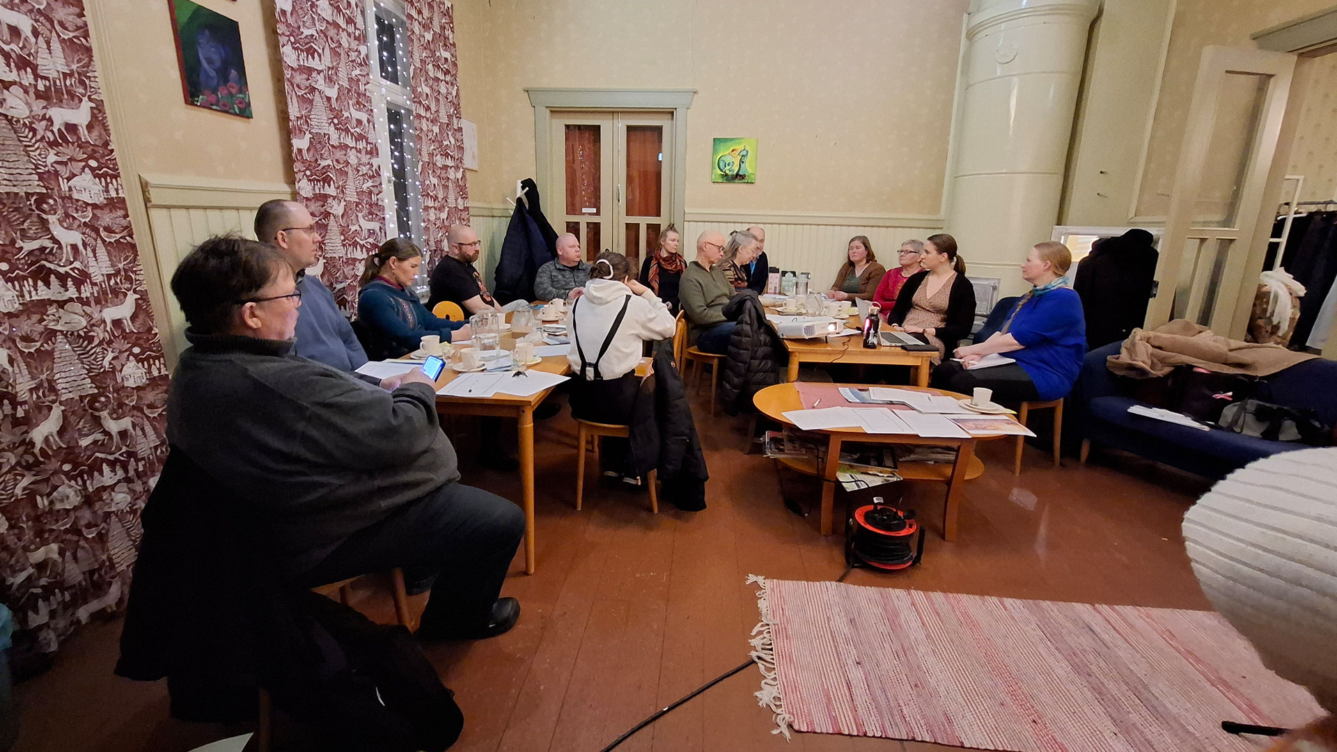 Ihmisiä istuu kahvilan pöytien ääressä. 