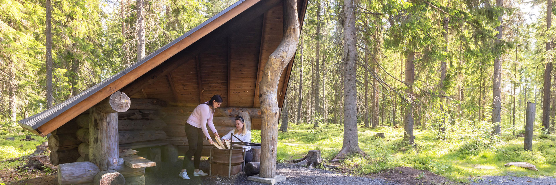 Kaksi naista on laavulla tekemässä tulia tulipaikalle.